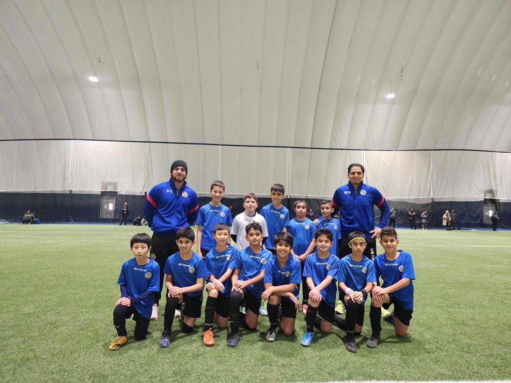 Mississauga United FC youth soccer players practicing teamwork on the field.