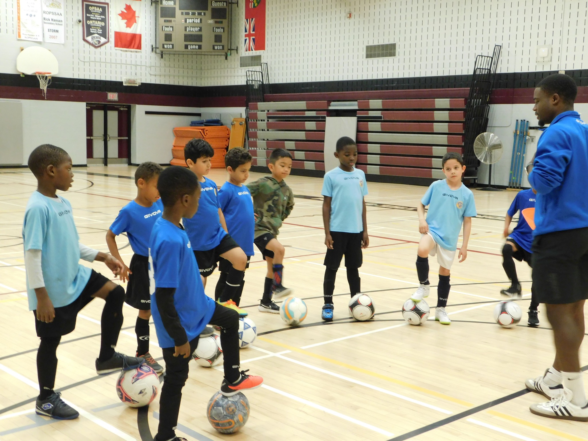 Children practicing beginner soccer drills indoors during Mississauga United FC Development I training session.