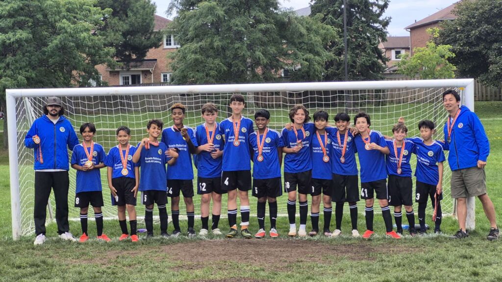 Mississauga United FC U12 championship team posing with coaches and medals